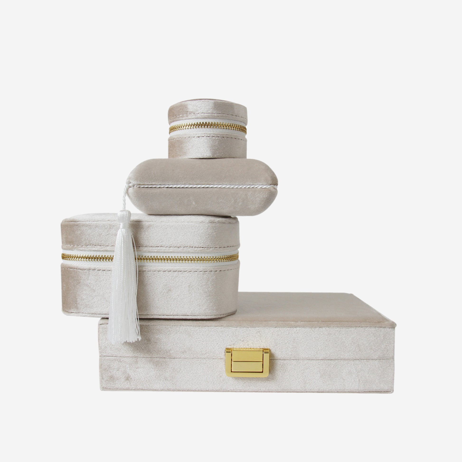 Stack of four champagne velvet jewellery boxes of different shapes and sizes on an off white background