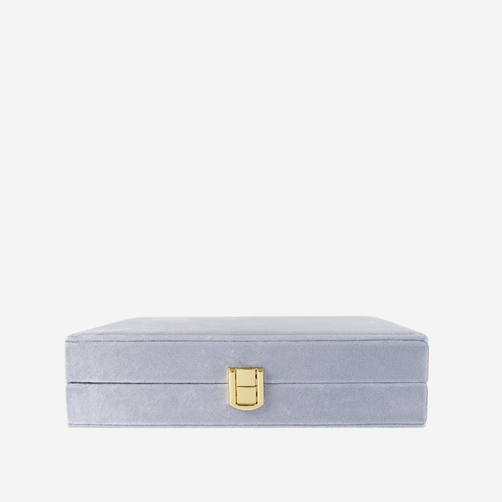Blue velvet closed jewellery box on an off white background