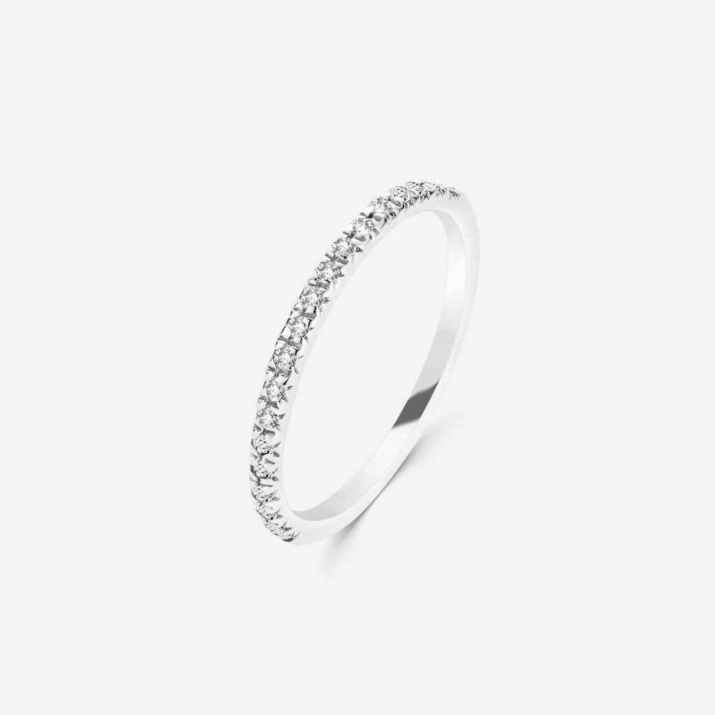 Silver half eternity ring set with diamonds on an off white background