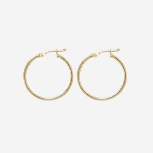 Pair of 14ct yellow gold medium hoop earrings on an off white background