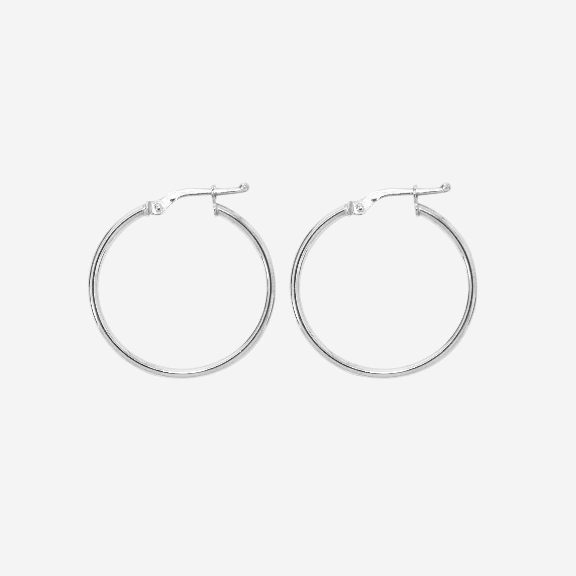 Pair of 14ct white gold medoim hoop earrings on an off white background