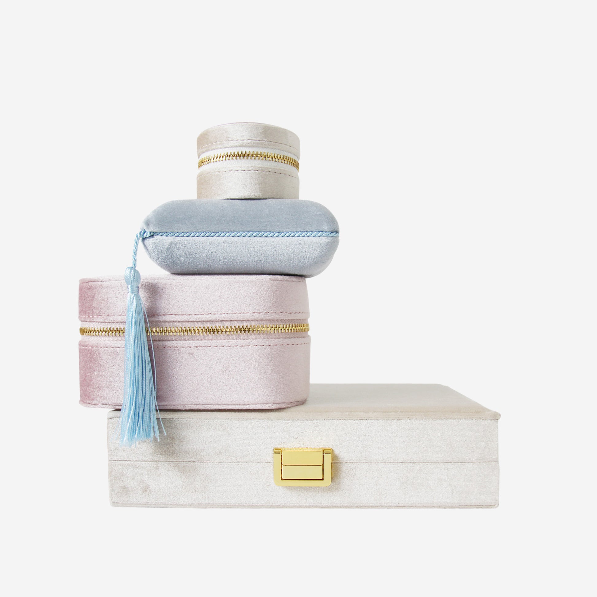Stack of four velvet jewellery boxes of different shapes,  sizes  and colours on an off white background