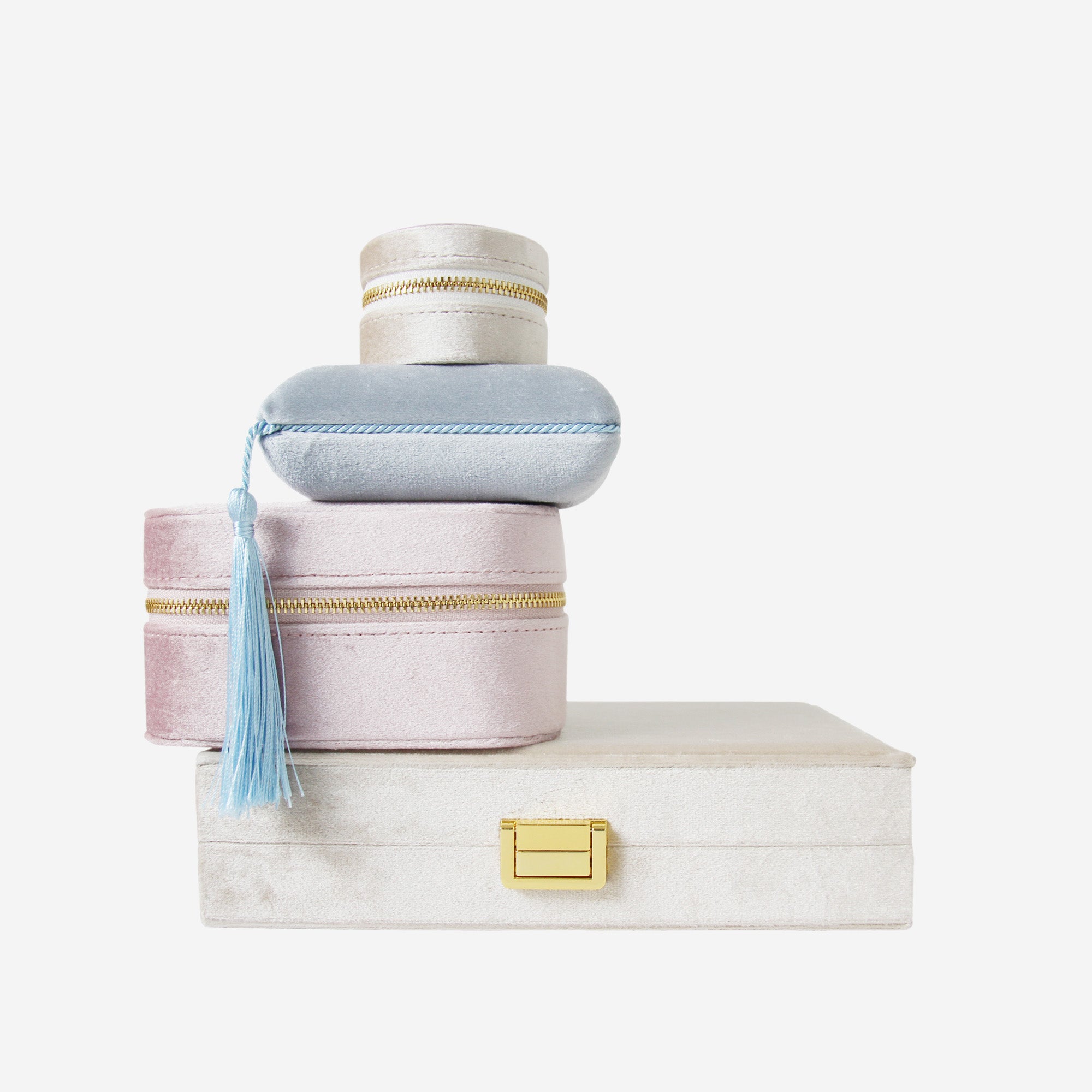 Stack of four velvet jewellery boxes of different shapes,  sizes  and colours on an off white background