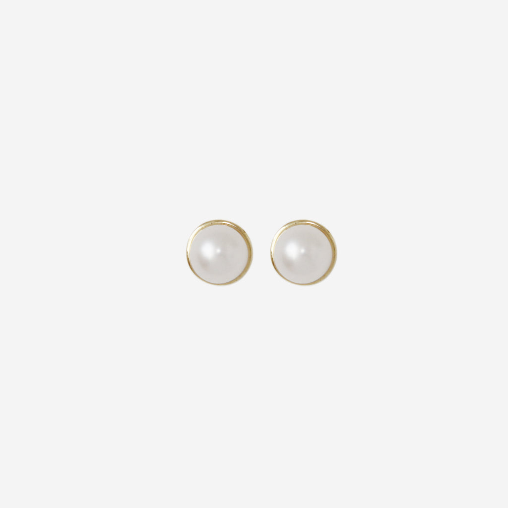 Pair of pearl stud earrings with 14ct gold posts on an off white background