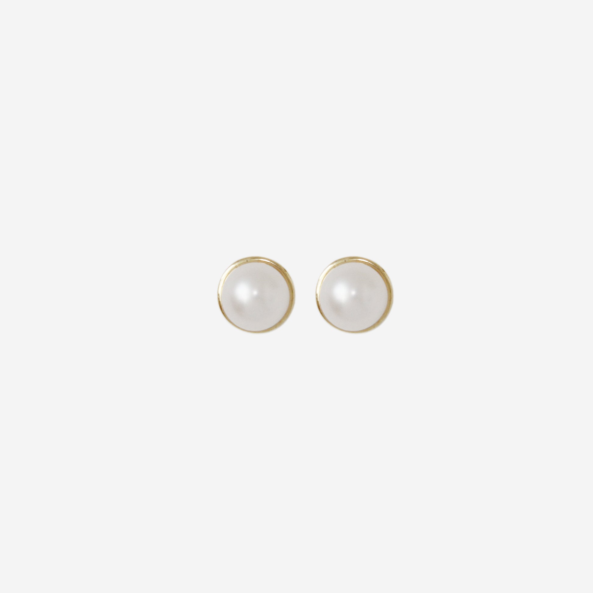 Pair of pearl stud earrings with 14ct gold posts on an off white background