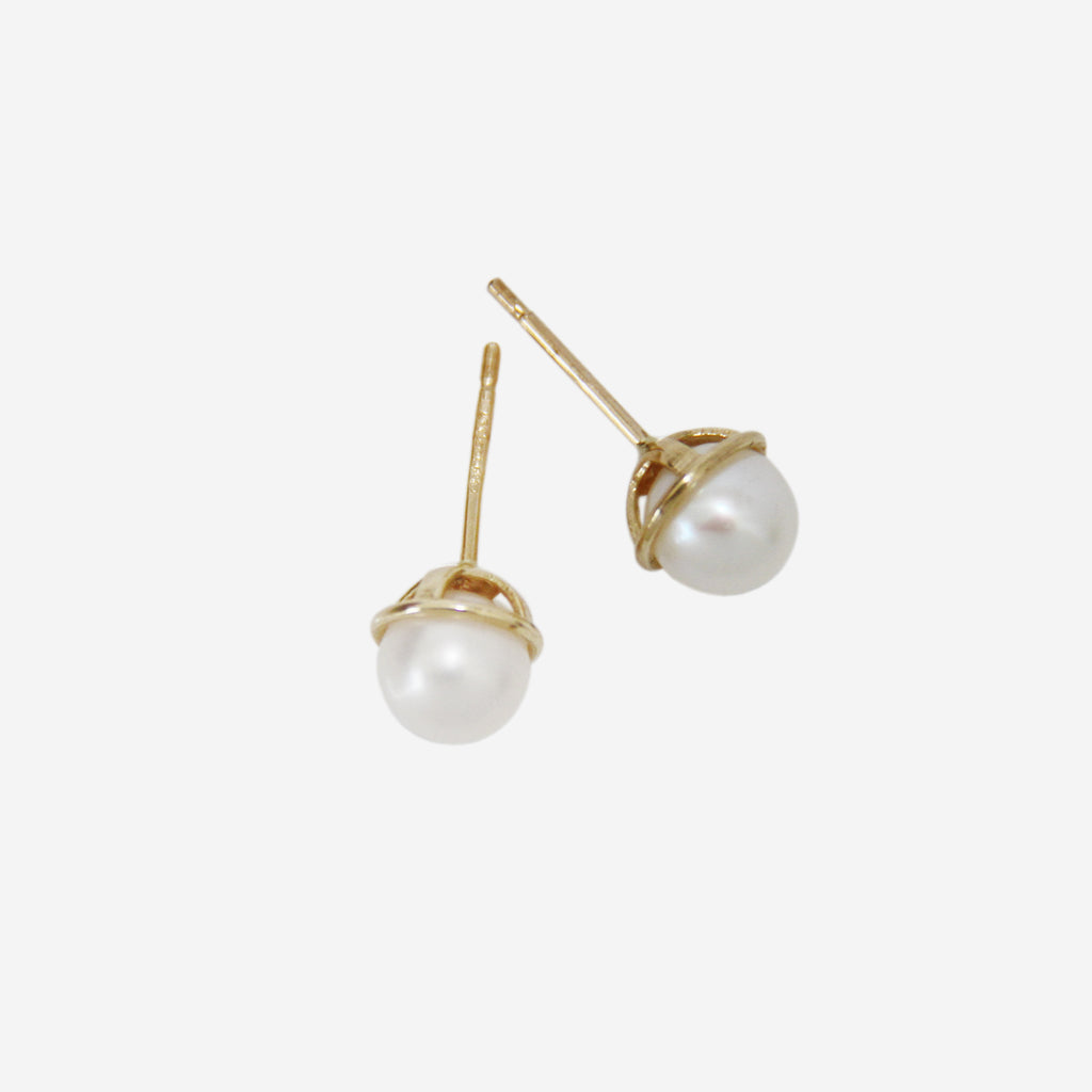 Pair of pearl stud earrings with 14ct gold posts on an off white background