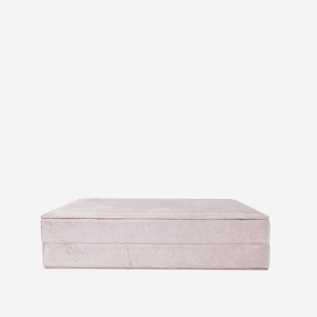 Pink velvet closed jewellery box on an off white background