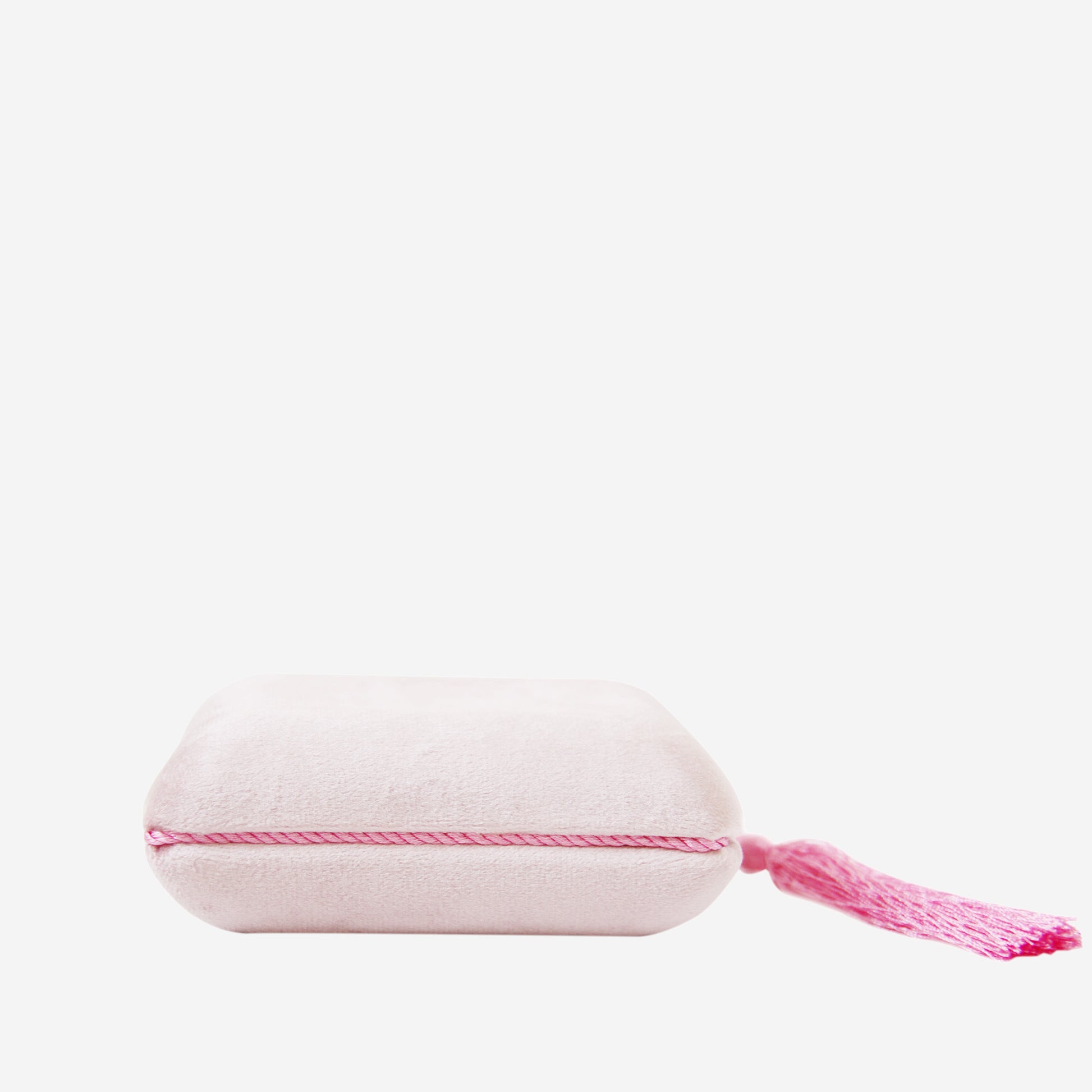Closed pink velvet jewellery box with tassel detail on an off white background
