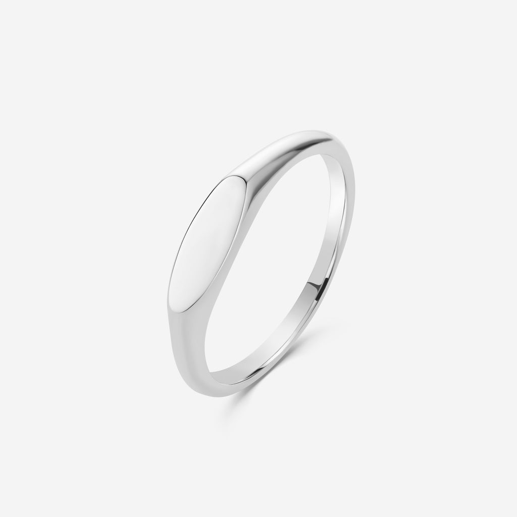 Silver oval signet ring on an off white background