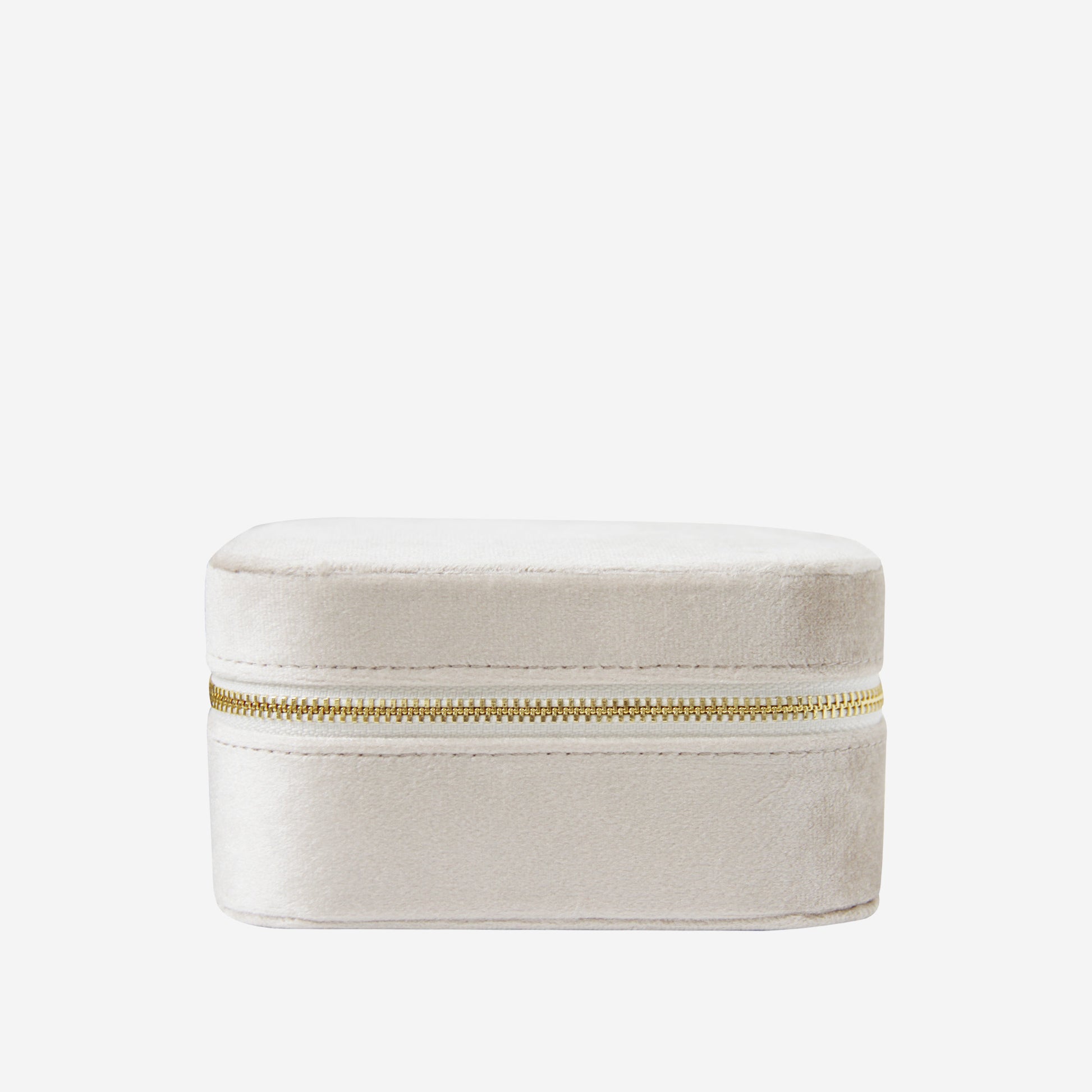 Closed champagne velvet travel jewelry box with a gold zipper on an off white background