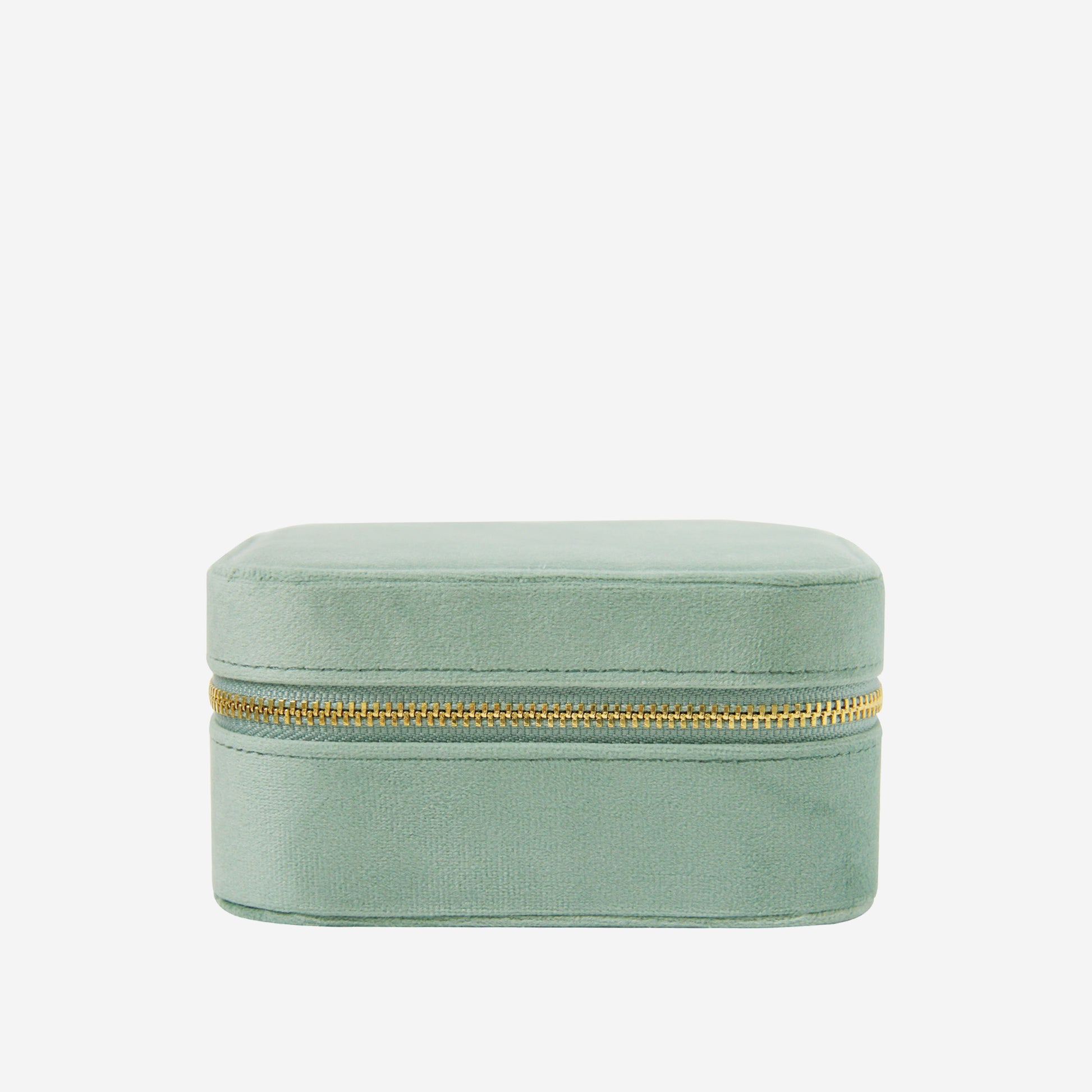 Closed green velvet travel jewelry box with a gold zipper on an off white background