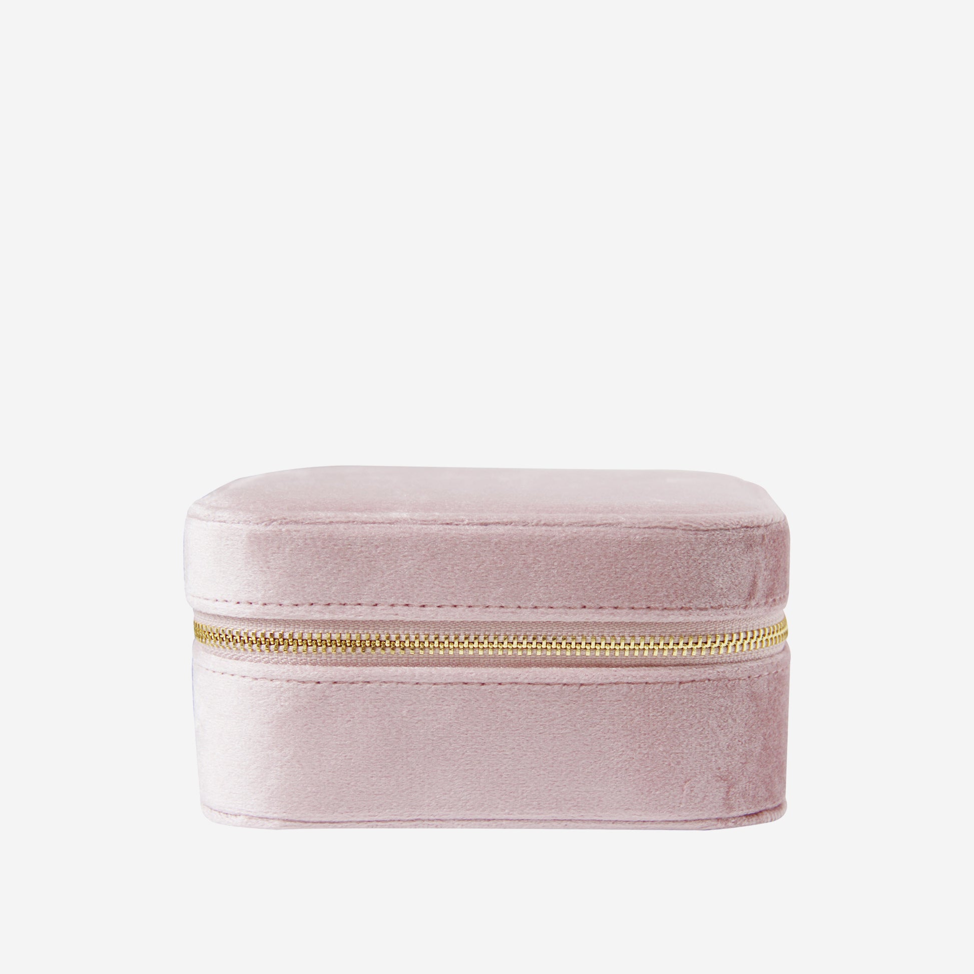 Closed pink velvet travel jewelry box with a gold zipper on an off white background
