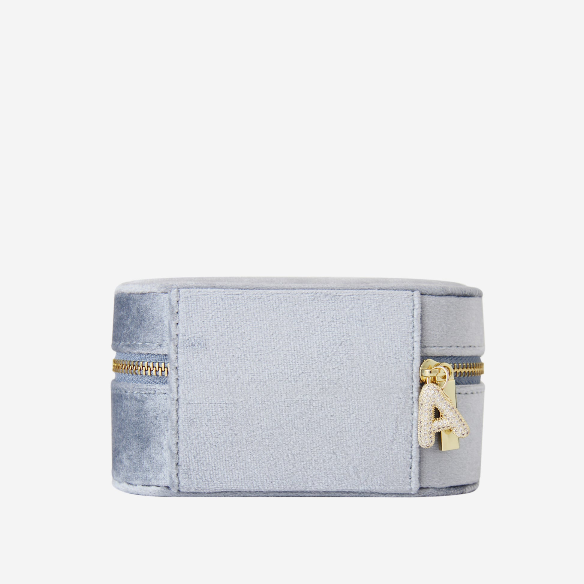 Blue velvet travel jewellery box with gold zipper and a crystal and gold letter A charm on an off white background