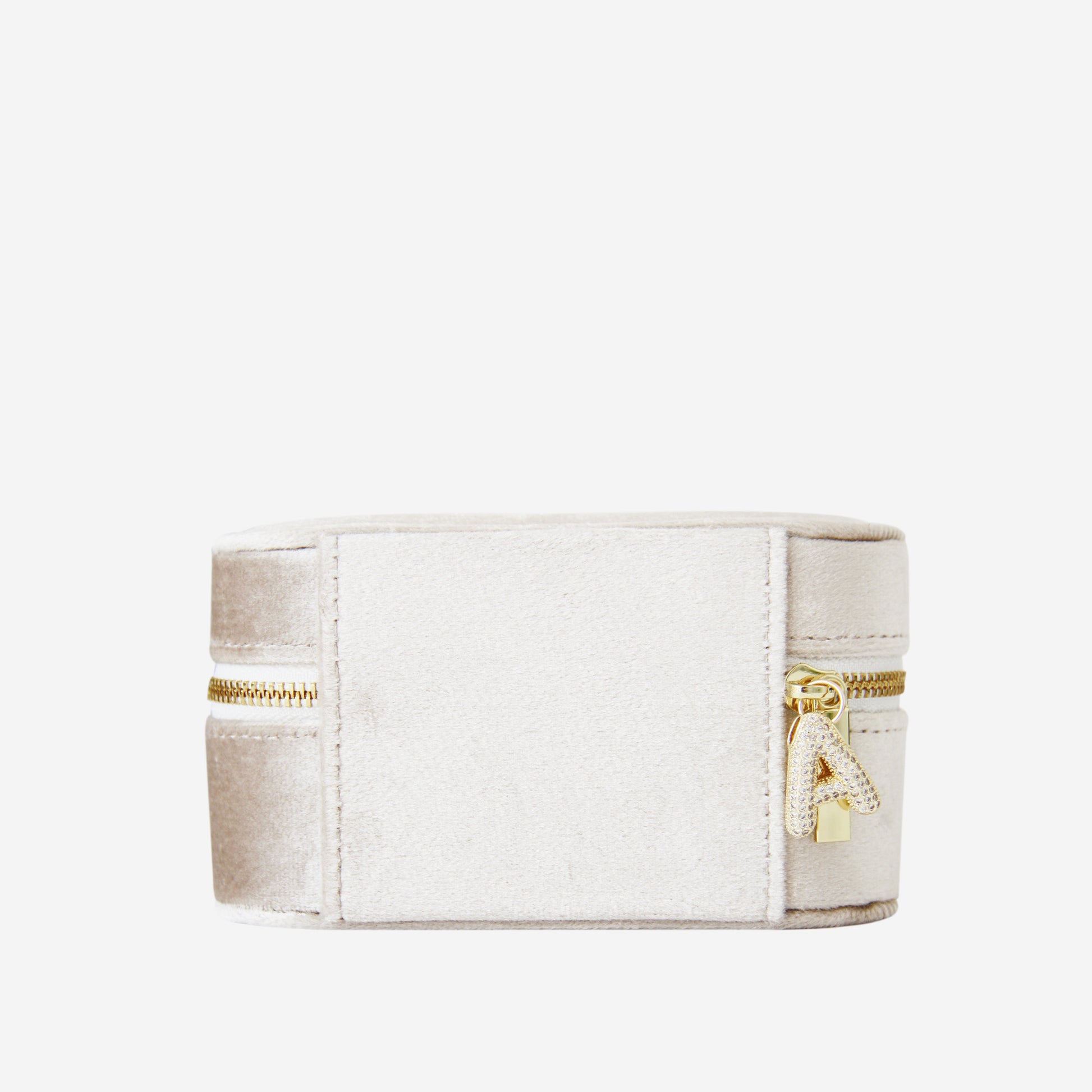 Champagne velvet travel jewellery box with gold zipper and a crystal and gold letter A charm on an off white background