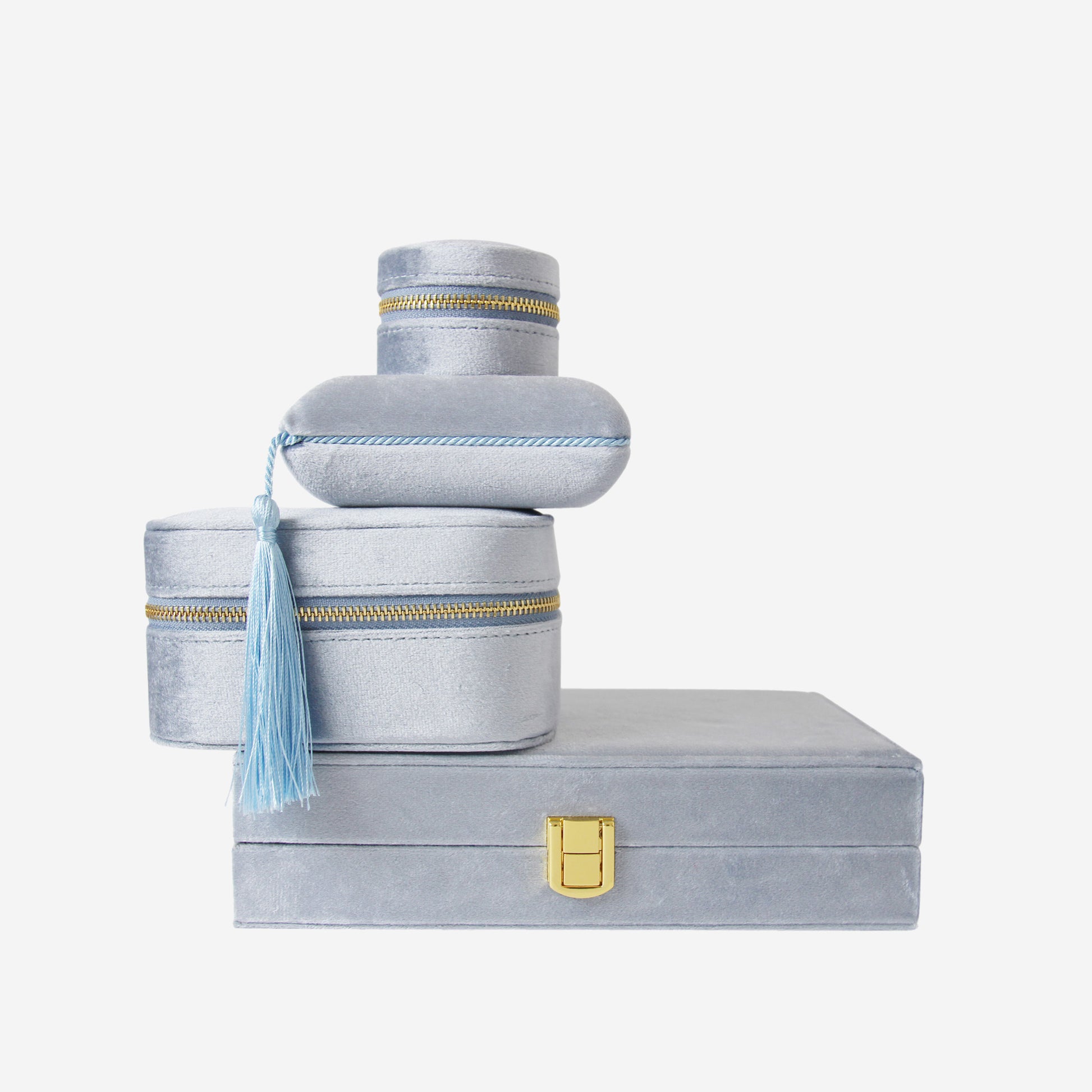 Stack of four blue velvet jewellery boxes of different shapes and sizes on an off white background
