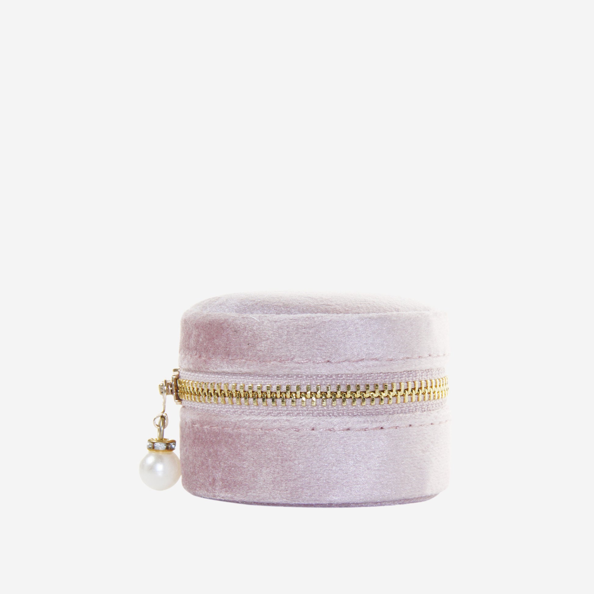 Small round pink velvet jewelry box with gold zipper and pearl charm on an off white background