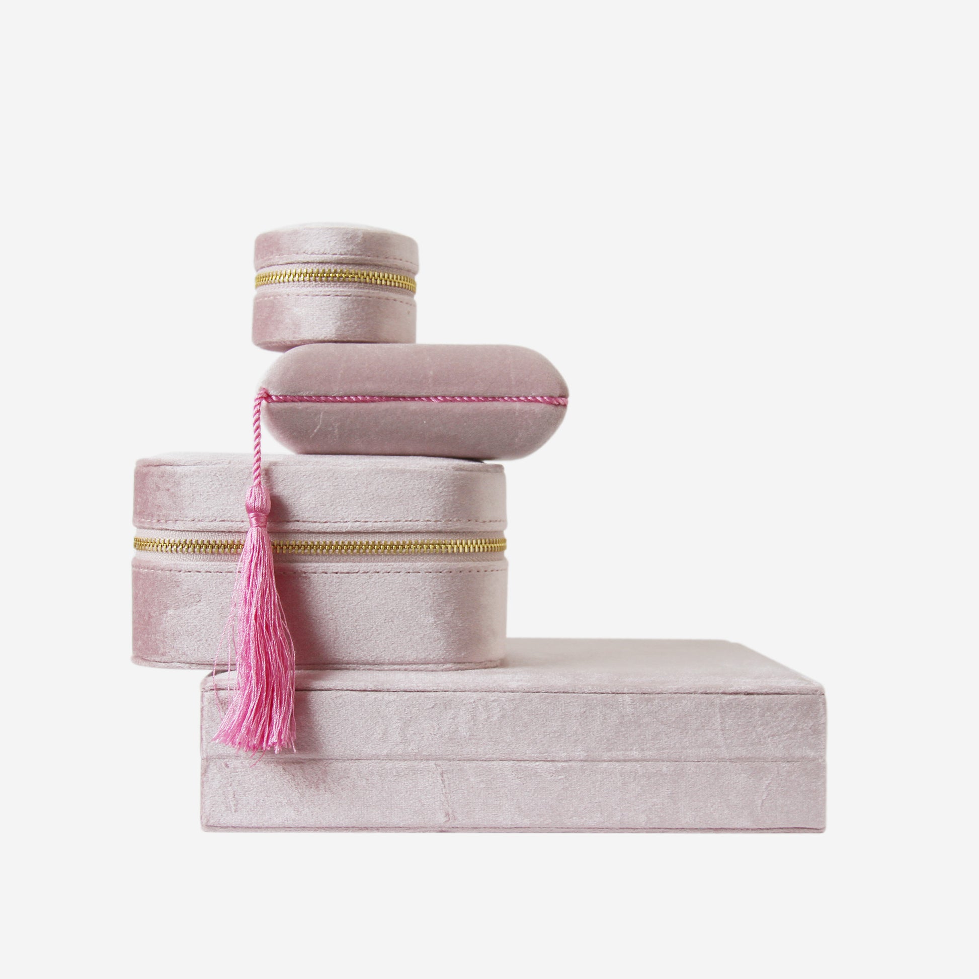 Stack of four pink velvet jewellery boxes of different shapes and sizes on an off white background