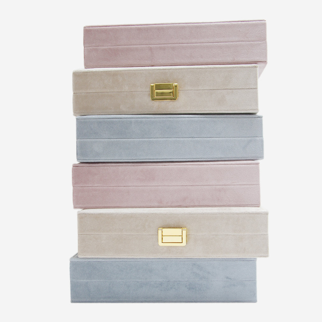 Stack of pastel-colored jewelry boxes with gold latches on an off white background