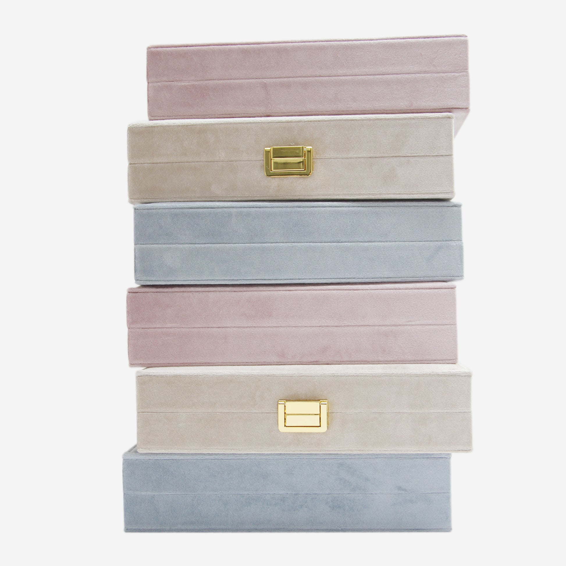 Stack of pastel-colored jewelry boxes with gold latches on an off white background
